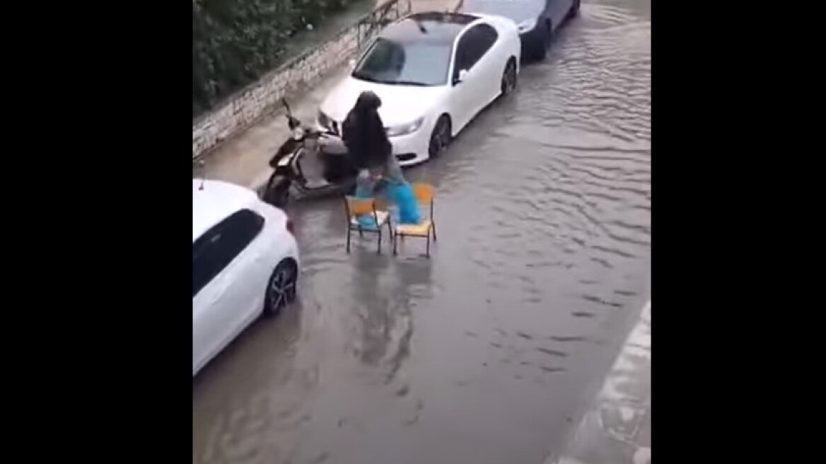 Κακοκαιρία: Έκανε ακροβατικά με καρέκλες για να περάσει τον πλημμυρισμένο δρόμο - Δείτε βίντεο