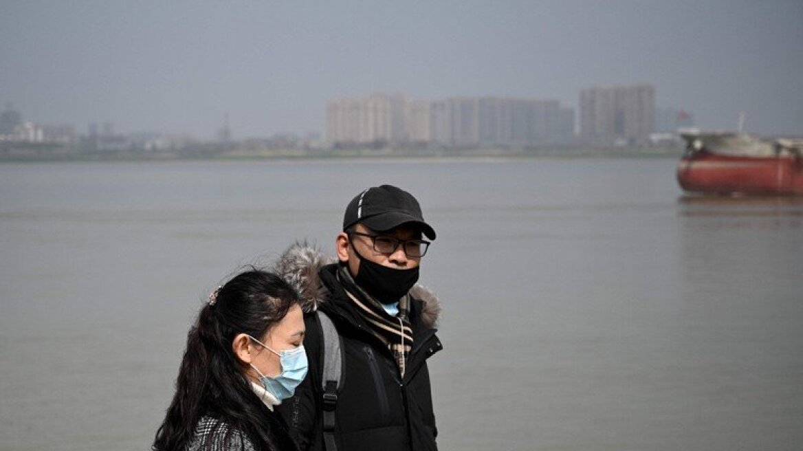 People-wearing-face-masks-walk-along-Juijiang-China-afp