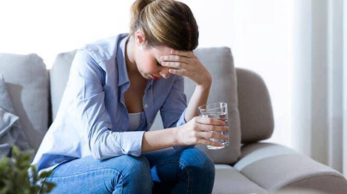 unhealthy-young-woman-with-headache-holding-glass-of-water-while-on-picture-id943130074-min
