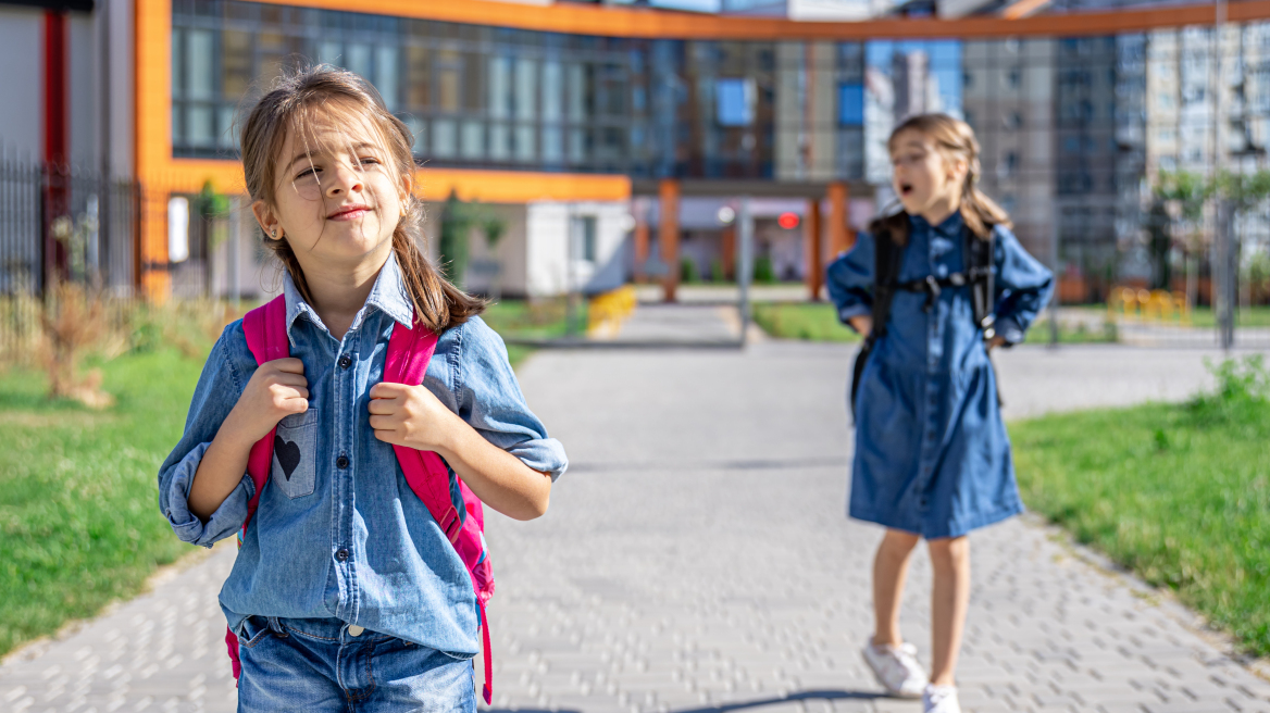 pupils-primary-school-girls-with-backpacks-near-building-outdoors-beginning-lessons-first-day-fall