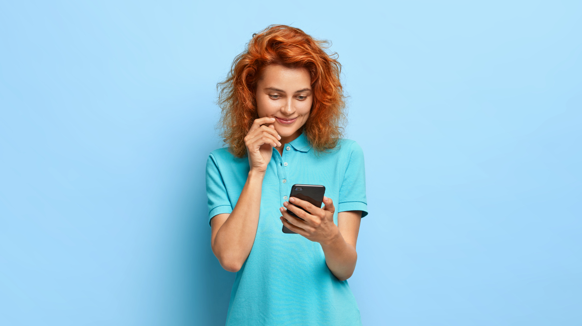 satisfied-lovely-ginger-woman-holds-mobile-phone