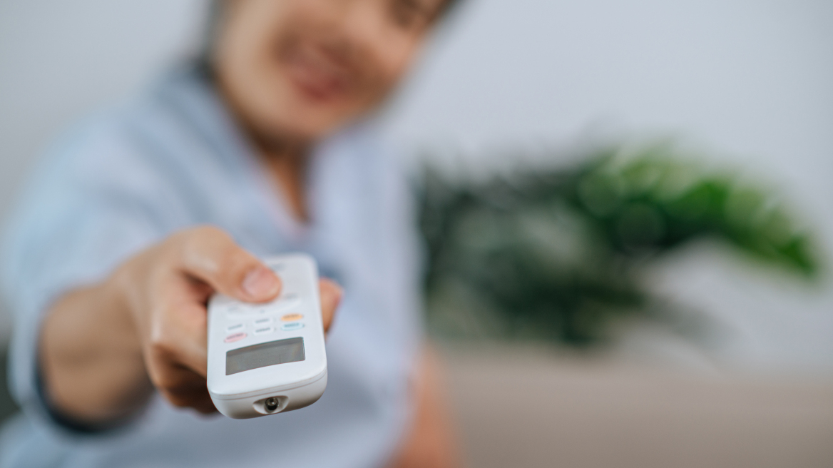 close-up-selective-focus-hand-woman-holding-use-remote-control-open-aircondition-living-room-home