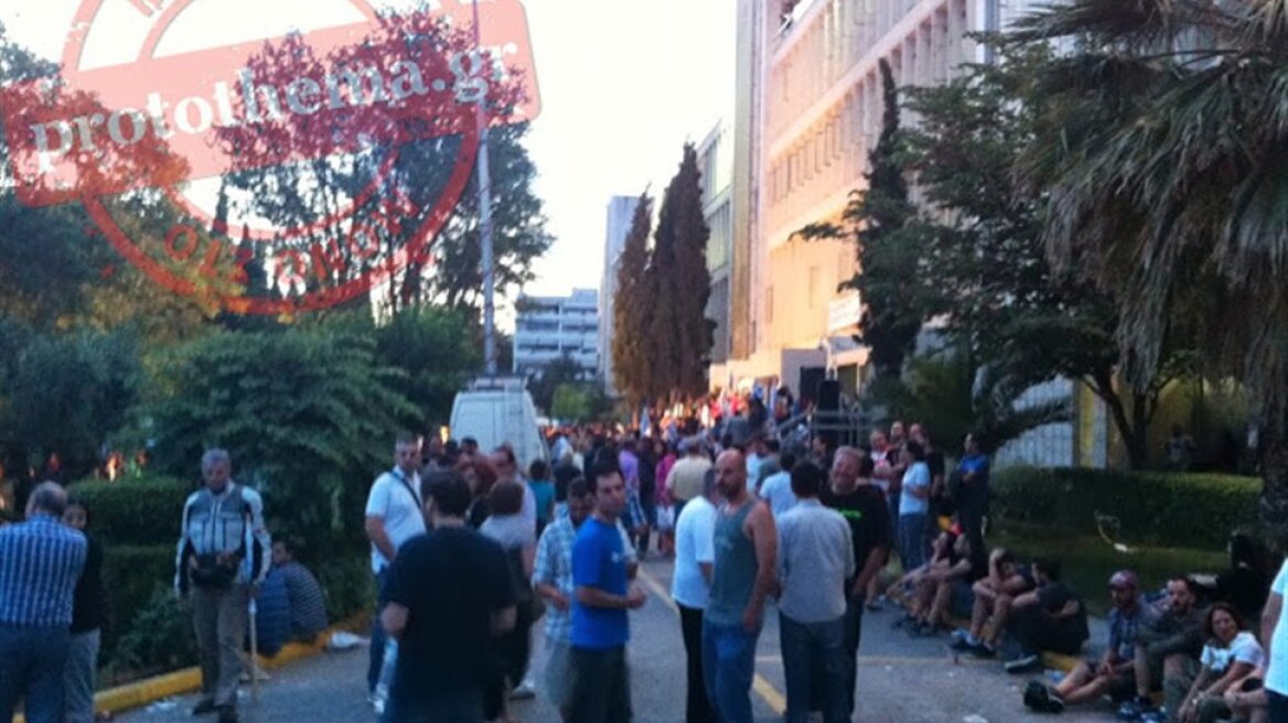 Workers remain outside the Greek national television building