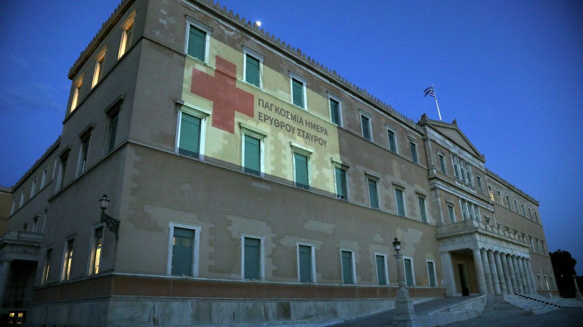 Mε το εμβληματικό κόκκινο χρώμα του Ερυθρού Σταυρού «ντύθηκε» η πρόσοψη της Βουλής