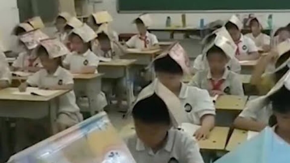 Chinese Teacher forces her pupils to hold books with their heads