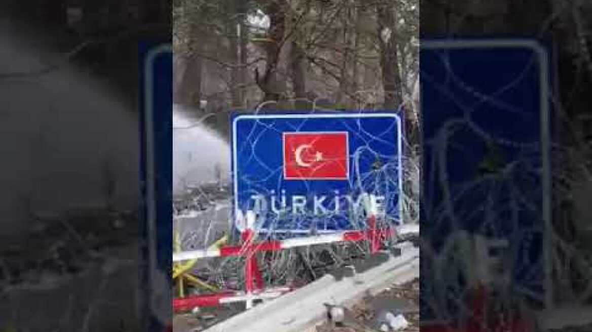 Συγκεντρωμένο πλήθος μπροστά στα σύνορα όπου ανάμεσα στους μετανάστες κυματίζει η αφγανική σημαία.