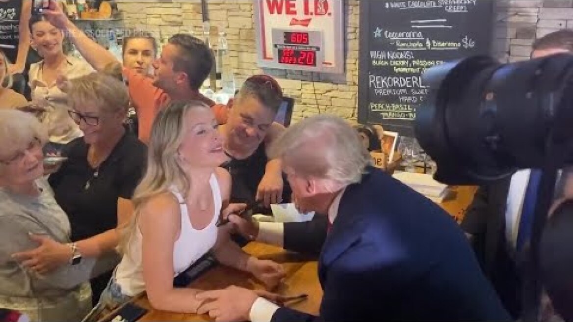 Trump autographs woman's tank top shirt at Iowa campaign stop
