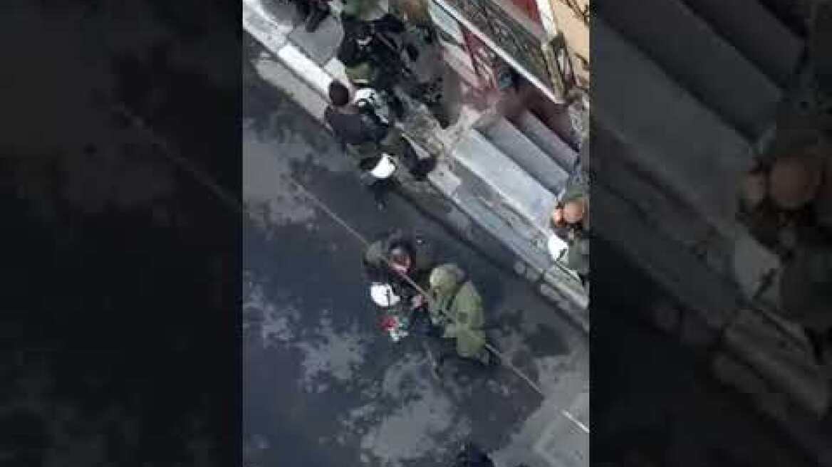 Αστυνομικός παίρνει την ανθοδέσμη απ το μνημείο και την πετά σε άλλον αστυνομικό .