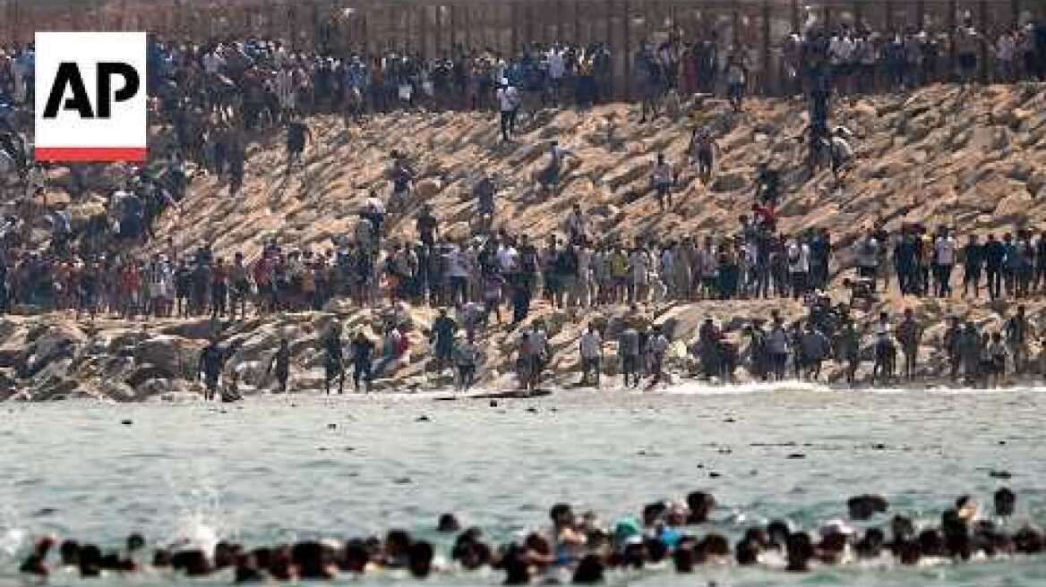 Thousands of migrants swim around the border from Morocco into Ceuta, Spain