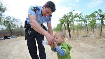 Συγκλονιστικές φωτογραφίες από τα σύνορα Ελλάδας-ΠΓΔΜ: Αστυνομικός ξεδιψά παιδάκι