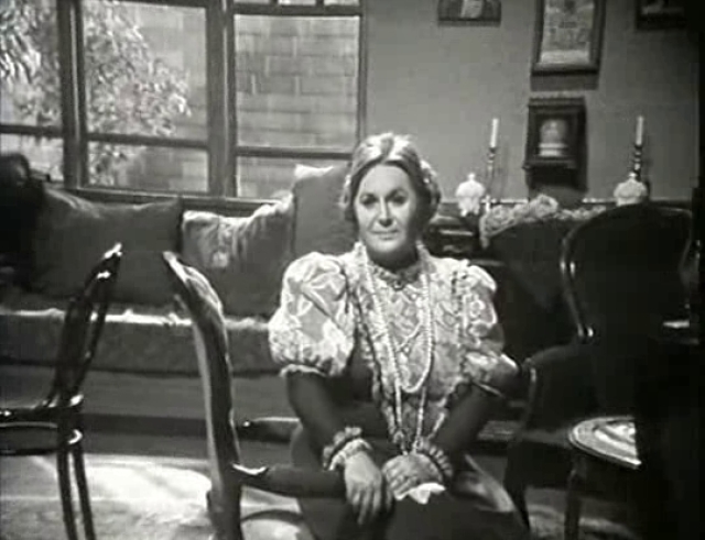 Betty Valasi sitting in a room in a television still